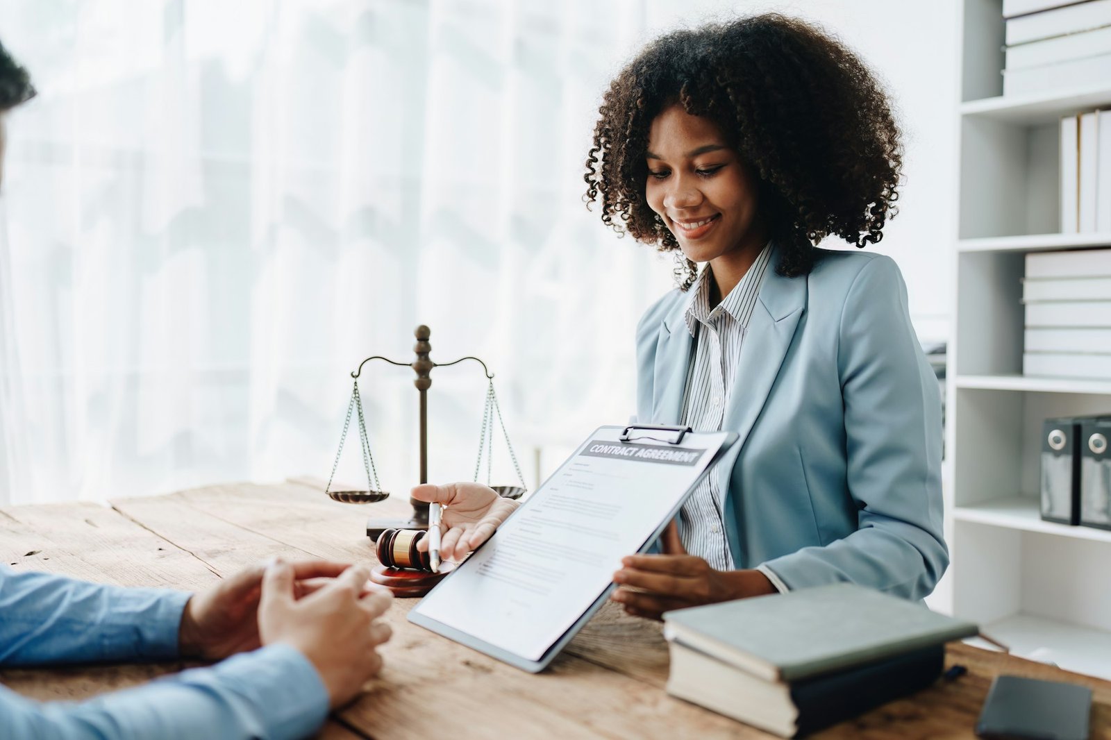 Young African American lawyer studying a case for a client and signing a legal contract to fight her